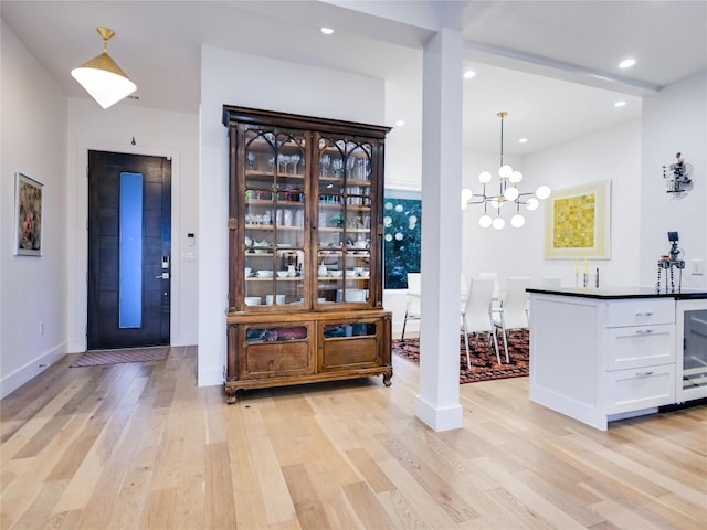 bar with light wood-style floors, recessed lighting, pendant lighting, and an inviting chandelier