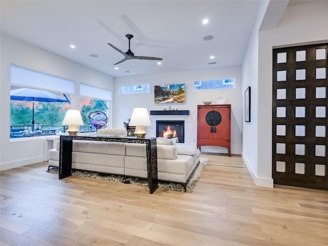 living area with light wood-type flooring, a glass covered fireplace, and recessed lighting