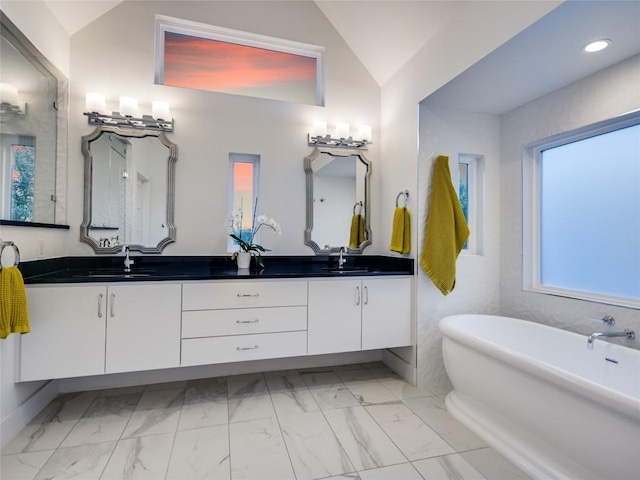 bathroom with a freestanding bath, marble finish floor, double vanity, and a sink