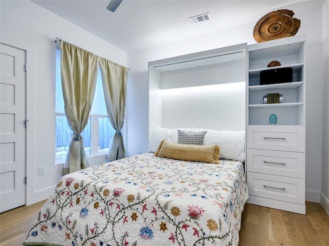 bedroom featuring ceiling fan, light wood finished floors, visible vents, and baseboards