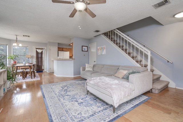 living room featuring light wood finished floors, stairway, and visible vents