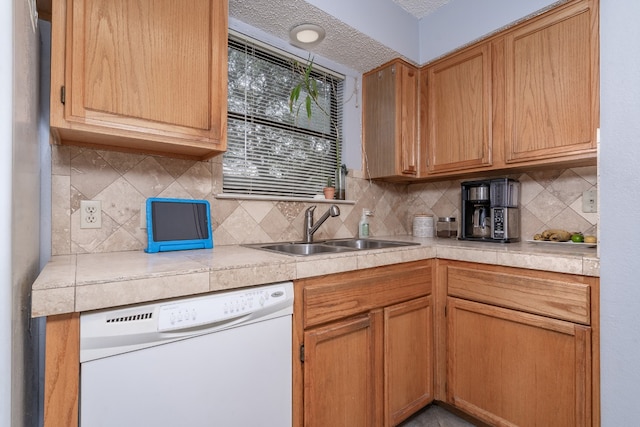 kitchen with light countertops, dishwasher, backsplash, and a sink