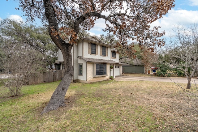 view of front facade with driveway, a front yard, and fence