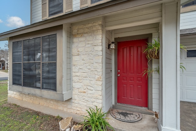 property entrance featuring a garage and stone siding