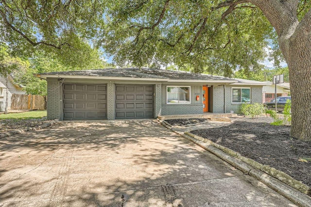 ranch-style home with a garage, driveway, brick siding, and fence