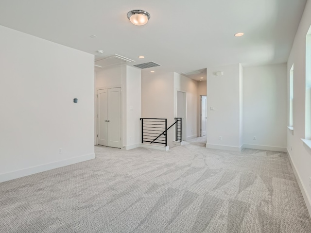 empty room with recessed lighting, light carpet, visible vents, baseboards, and attic access