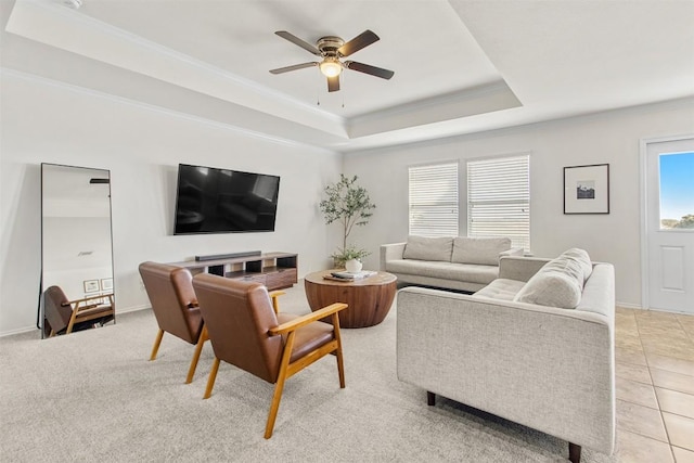 living room featuring light tile patterned floors, ceiling fan, baseboards, a raised ceiling, and crown molding