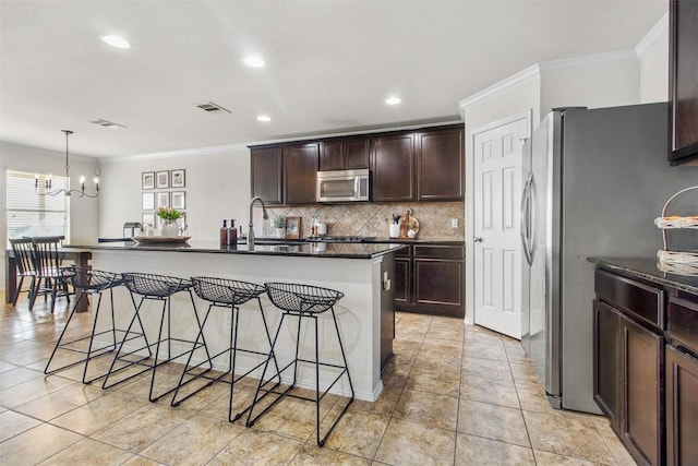 kitchen featuring visible vents, decorative backsplash, appliances with stainless steel finishes, ornamental molding, and a kitchen breakfast bar