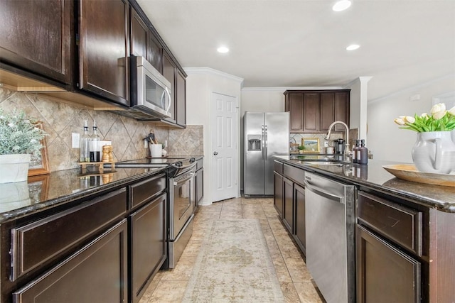 kitchen featuring stainless steel appliances, dark stone countertops, dark brown cabinetry, and a sink