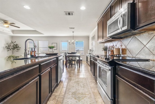 kitchen with visible vents, backsplash, appliances with stainless steel finishes, a sink, and dark brown cabinets