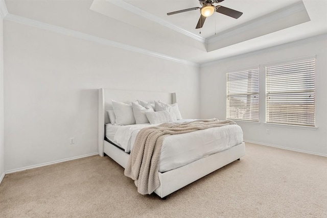 bedroom featuring a tray ceiling, light colored carpet, crown molding, and baseboards