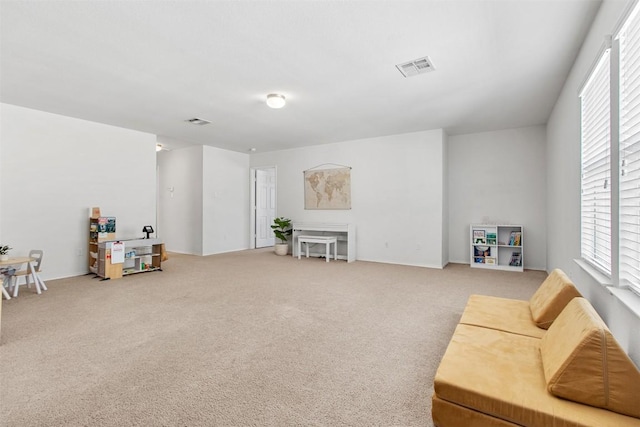 living area featuring plenty of natural light, carpet flooring, and visible vents