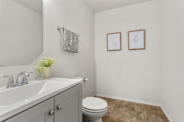 bathroom featuring vanity, toilet, and baseboards