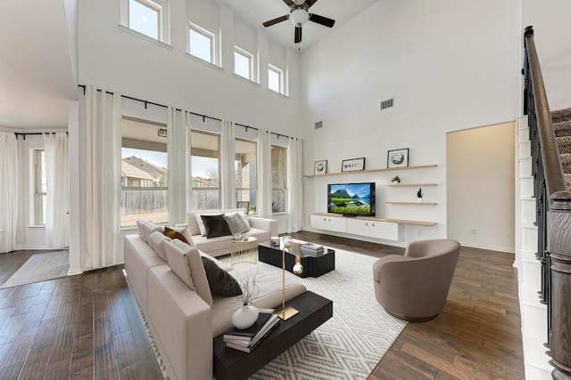 living area with visible vents, a ceiling fan, a high ceiling, and dark wood-type flooring