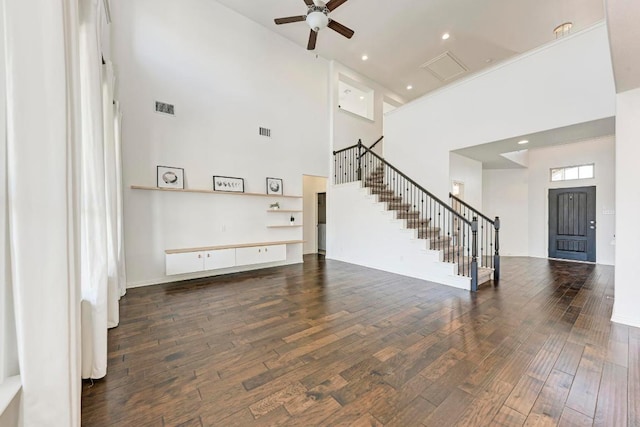 unfurnished living room featuring a ceiling fan, visible vents, stairway, and wood finished floors