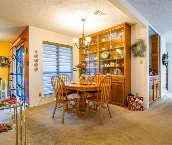 carpeted dining room featuring a chandelier, a textured ceiling, and visible vents