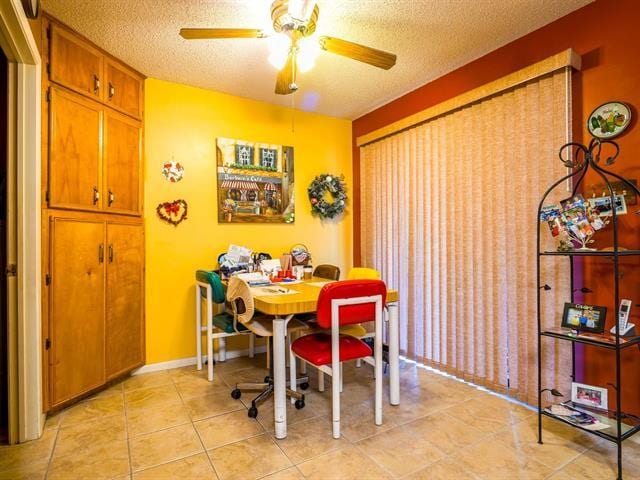 dining space with light tile patterned floors, baseboards, a ceiling fan, and a textured ceiling