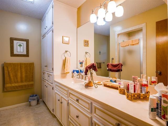 full bathroom with an inviting chandelier, a stall shower, vanity, a textured ceiling, and tile patterned flooring