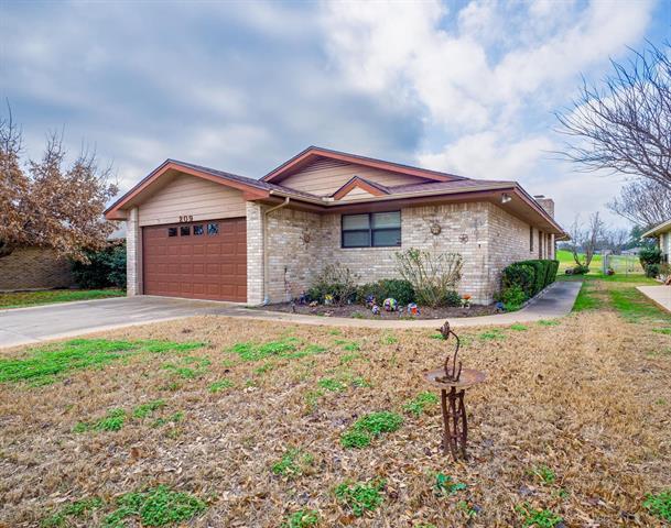 single story home featuring driveway, brick siding, a chimney, and an attached garage