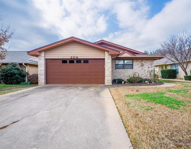 view of front facade with an attached garage, a front lawn, concrete driveway, and brick siding