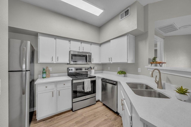 kitchen featuring visible vents, appliances with stainless steel finishes, light countertops, light wood-type flooring, and a sink