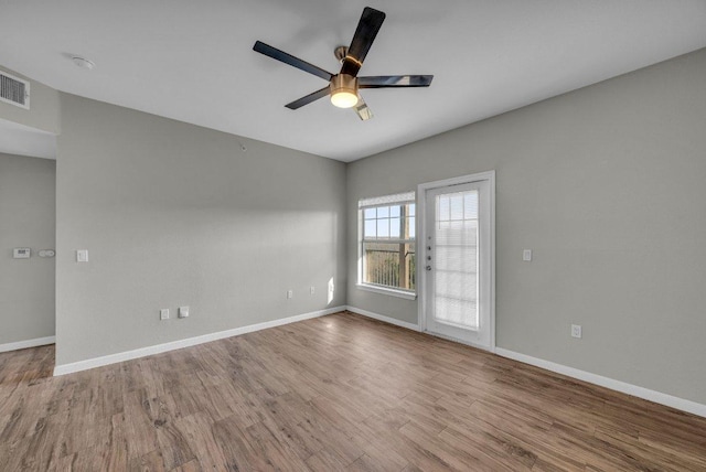 spare room featuring ceiling fan, baseboards, and wood finished floors