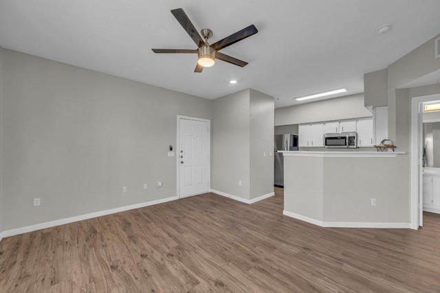 unfurnished living room with visible vents, wood finished floors, a ceiling fan, and baseboards