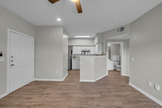 kitchen featuring visible vents, white cabinets, wood finished floors, stainless steel appliances, and light countertops