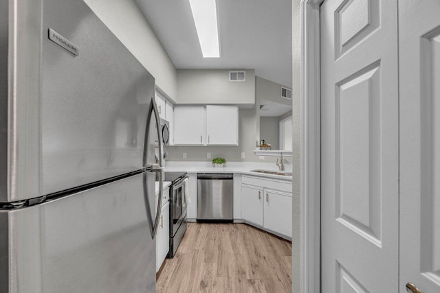 kitchen with visible vents, stainless steel appliances, light countertops, white cabinetry, and a sink