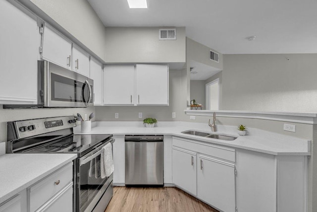 kitchen featuring stainless steel appliances, light countertops, visible vents, white cabinets, and a sink