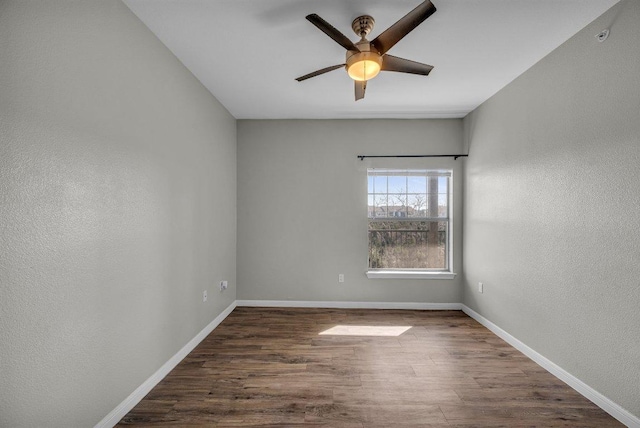 empty room featuring a ceiling fan, a textured wall, baseboards, and wood finished floors