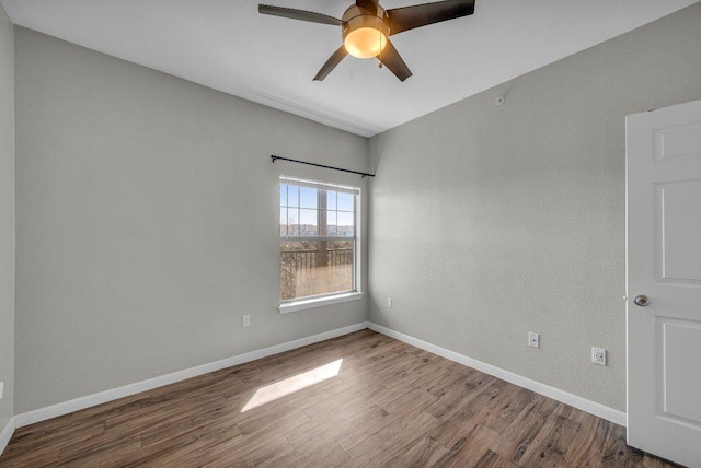 spare room featuring a ceiling fan, baseboards, and wood finished floors