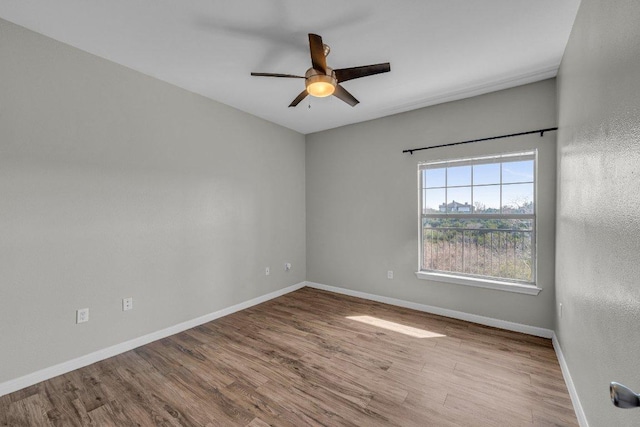 empty room featuring a ceiling fan, baseboards, and wood finished floors