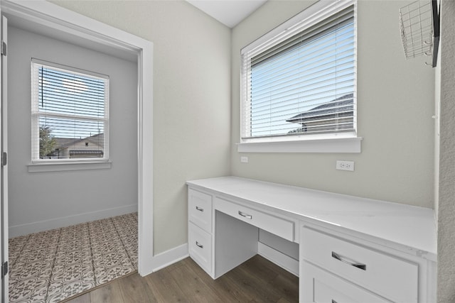 office featuring built in desk, dark wood finished floors, a wealth of natural light, and baseboards