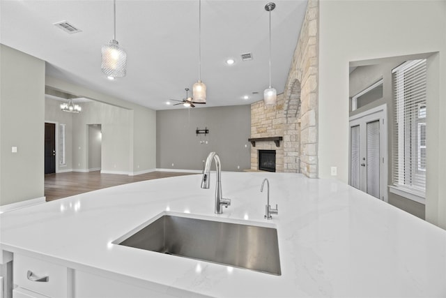 kitchen featuring a fireplace, visible vents, open floor plan, a sink, and ceiling fan