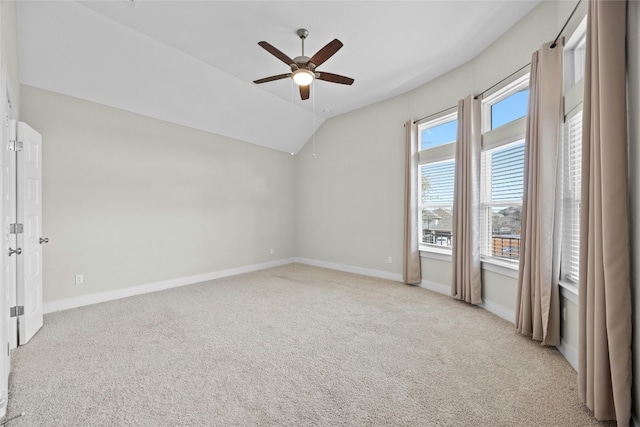 carpeted empty room with vaulted ceiling, a ceiling fan, and baseboards