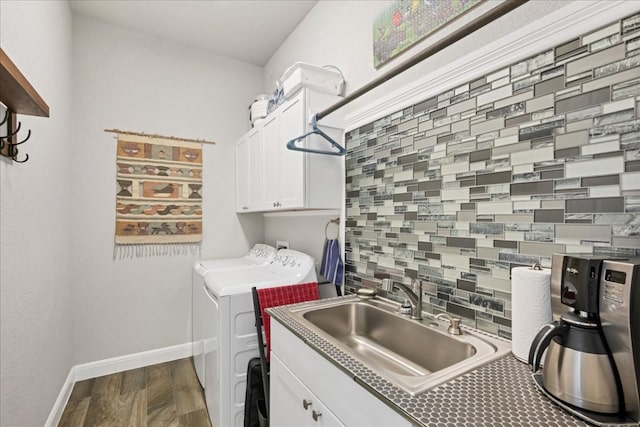 washroom featuring cabinet space, baseboards, washer and clothes dryer, dark wood-type flooring, and a sink