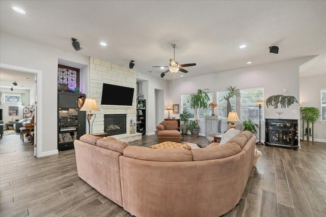 living room featuring recessed lighting, a fireplace, baseboards, and wood finished floors