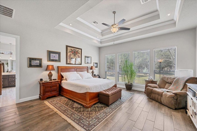 bedroom featuring visible vents, a tray ceiling, and wood finished floors