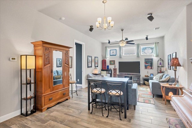 dining room featuring light wood-type flooring, baseboards, visible vents, and ceiling fan with notable chandelier