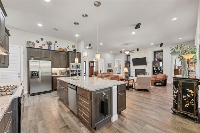 kitchen featuring a fireplace, visible vents, stainless steel appliances, and dark brown cabinets