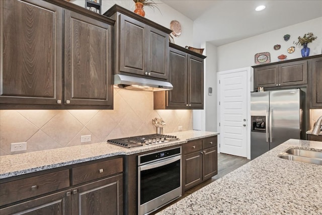 kitchen featuring stainless steel appliances, a sink, under cabinet range hood, and dark brown cabinetry