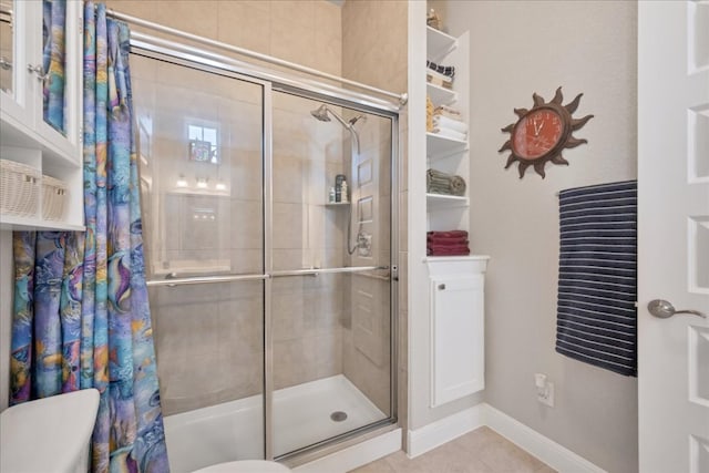 bathroom with tile patterned flooring, tiled shower, and baseboards