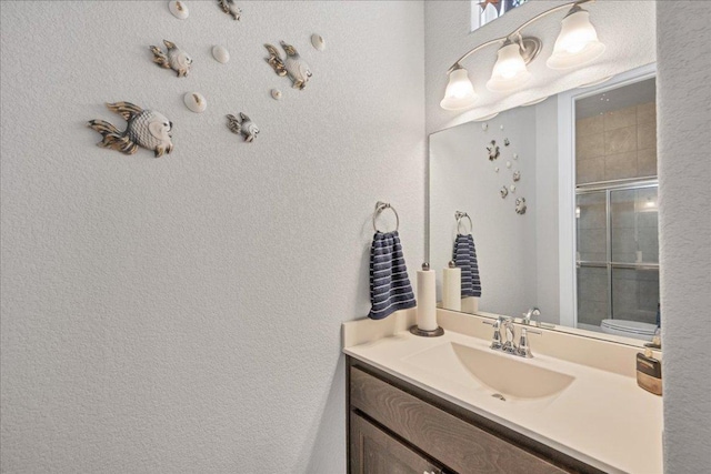 bathroom featuring a stall shower, a textured wall, and vanity