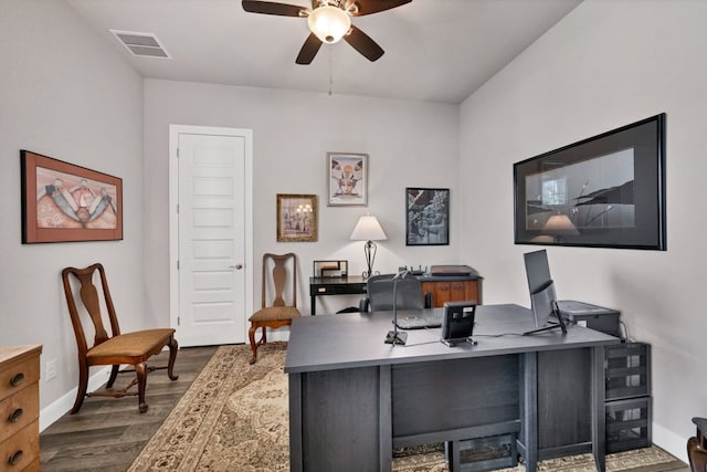 office area with baseboards, dark wood finished floors, visible vents, and a ceiling fan