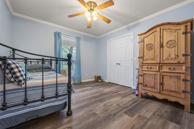 bedroom with baseboards, ceiling fan, dark wood-style flooring, crown molding, and a closet