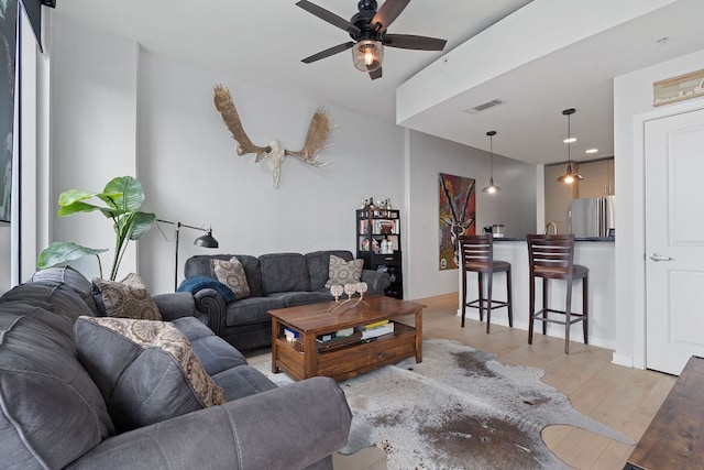 living area with light wood-style flooring, a ceiling fan, and visible vents