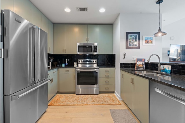 kitchen with visible vents, backsplash, light wood-style flooring, stainless steel appliances, and a sink