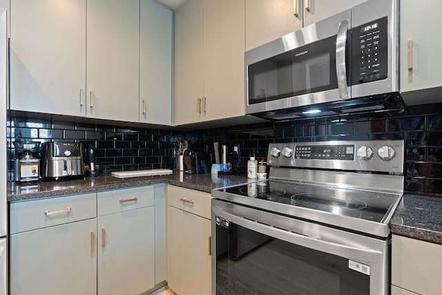 kitchen with stainless steel appliances, white cabinetry, backsplash, and dark stone counters