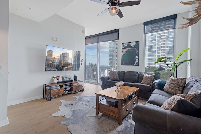 living area featuring a wealth of natural light, ceiling fan, light wood-type flooring, and baseboards